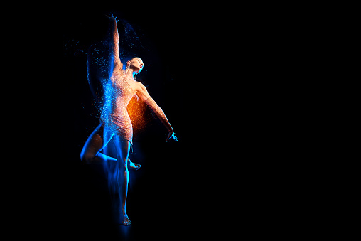 Fine art portrait of beautiful woman dancer in blue sparkles. Mixed lighting photography.