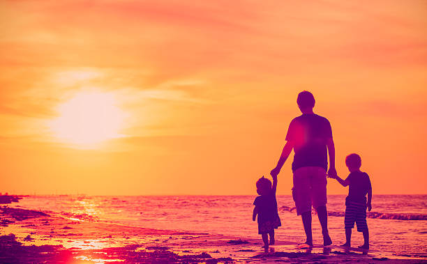 istock father and two kids walking on beach at sunset 610161456
