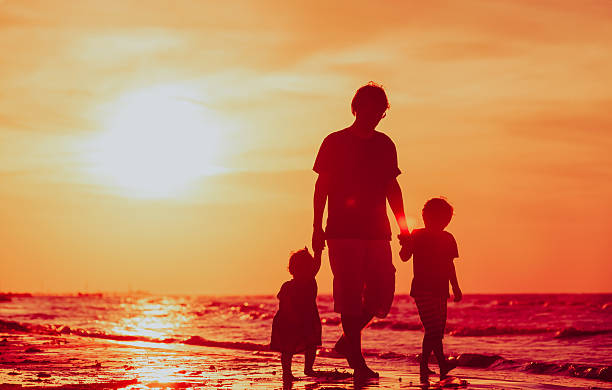 istock father and two kids walking on beach at sunset 610161538