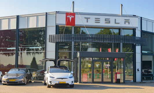 Duiven, The Netherlands - September 7, 2016: White Tesla Model X P90D all-electric crossover SUV and Model S electric car at a Tesla dealership. The Tesla Model X is a full-sized all-electric crossover SUV made by Tesla Motors that uses falcon wing doors. Other Tesla Model S cars are parked in the background.