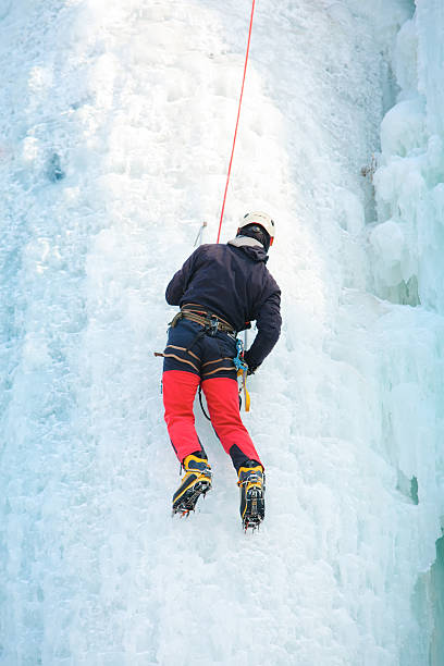 istock Man climbing frozen waterfall 610219200