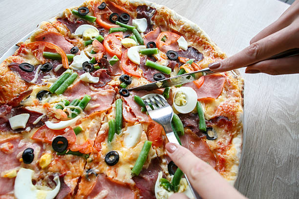 istock Slicing fresh pizza with pepperoni and vegetables 610220274