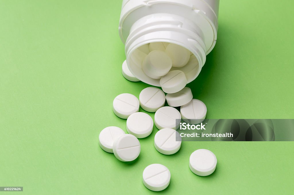 Round white pills and plastic pill bottle Heap of round white tablets and plastic pills bottle Aspirin Stock Photo