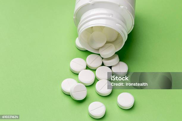 Round White Pills And Plastic Pill Bottle Stock Photo - Download Image Now - Aspirin, Bottle, Green Background