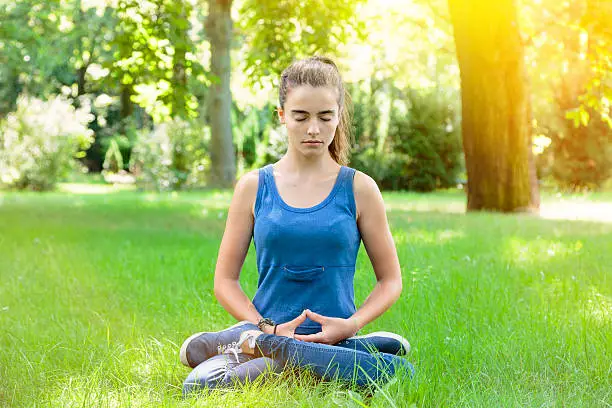 meditating teenage girl in a park