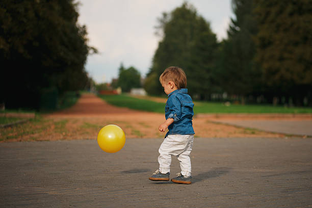 istock little boy playing with yellow ball 610226622