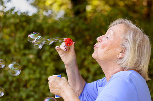 istock Attractive senior woman blowing soap bubbles 610228152