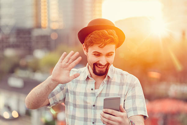 Man waving with hand on video call Smiling man saying hello on a video call cityscape videos stock pictures, royalty-free photos & images