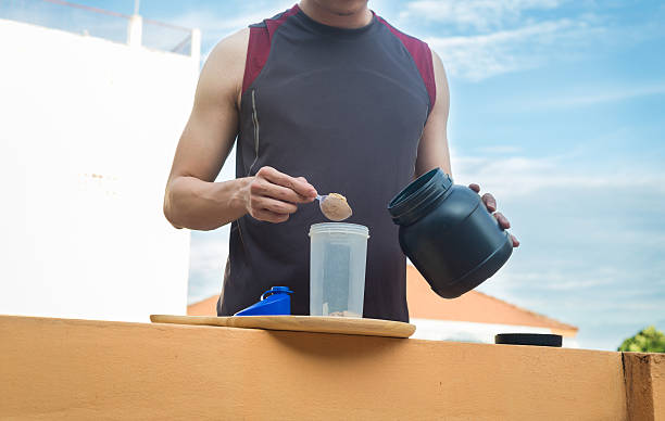 estilo de vida saudável, o homem derrama soro de leite na garrafa. - creatine nutritional supplement men human muscle - fotografias e filmes do acervo