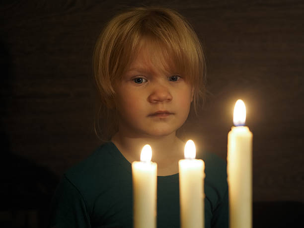 istock Little girl looks at three large candles 610232628