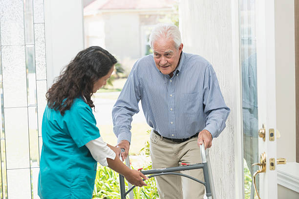 istock Home healthcare worker helping elderly man with walker 610233360