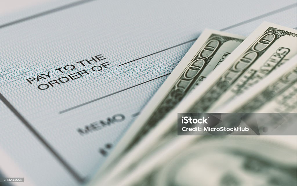 Personal Check and American Dollars With Selective Focus Close-up picture of a personal check and American Dollars with selective focus. Great use for financial concepts. Paycheck Stock Photo
