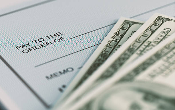 Personal Check and American Dollars With Selective Focus Close-up picture of a personal check and American Dollars with selective focus. Great use for financial concepts. paycheck photos stock pictures, royalty-free photos & images