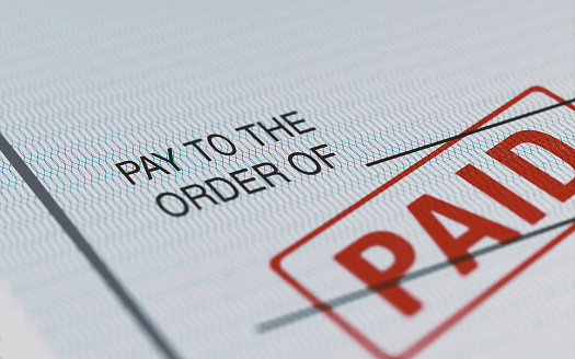 Close-up picture of a personal check with red paid stamp and selective focus. Great use for financial concepts.