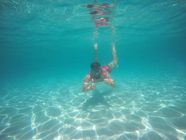 istock Man in glasses with thumbs up diving underwater 610235918
