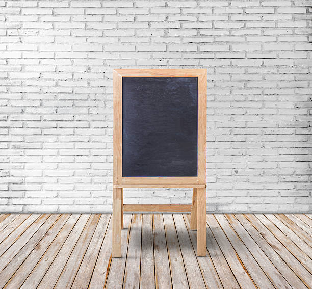 istock Blank blackboard on wood floor and white brick wall background 610236474