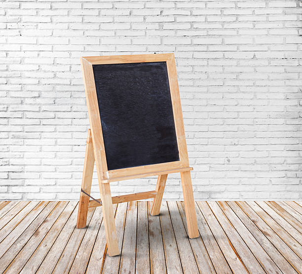 istock Blank blackboard on wood floor and white brick wall background 610236662