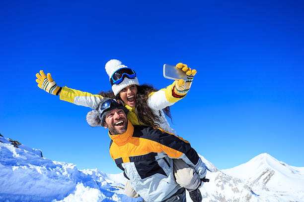 陽気な若いカップルのスキーヤーは楽しんで、冬の自分撮りを作る - バンスコ 写真 ストックフォトと画像