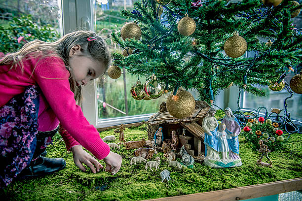 Girl of Four Playing with Figurines at Nativity Scene, Europe stock photo