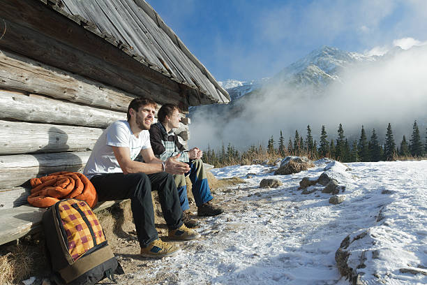 Dos amigos relajándose en un banco de madera en las montañas de invierno al aire libre - foto de stock