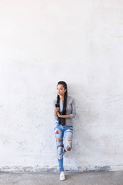 istock Pensive young asian woman leaning back on blank wall 610241158