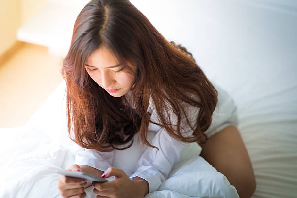 istock girl using a mobile phone lying on the bed 610241488