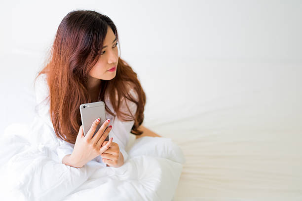 istock girl using a mobile phone lying on the bed 610241636