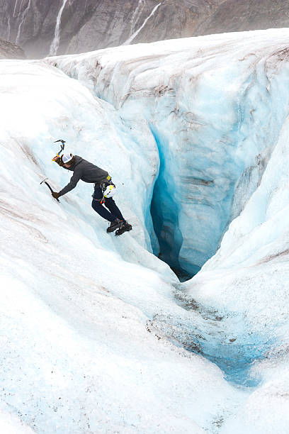grimpeur sur glace descendant une crevasse - crevasse photos et images de collection