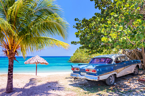 Antiguo coche americano oldtimer aparcado en una playa de Cuba photo