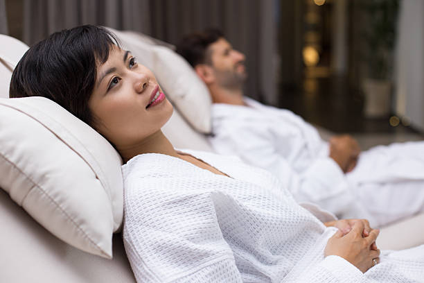 istock Smiling woman and man lying on deckchairs in spa 610250172
