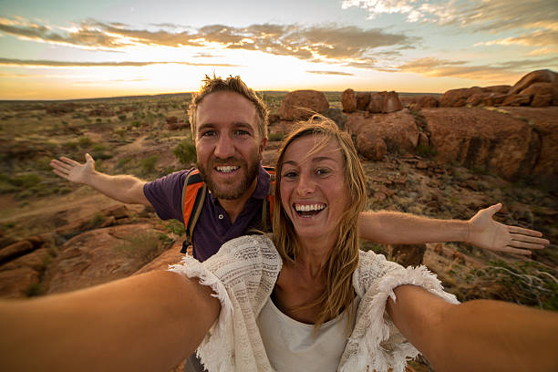 joven pareja toma retrato selfie con espectacular paisaje al amanecer - devils marbles fotografías e imágenes de stock