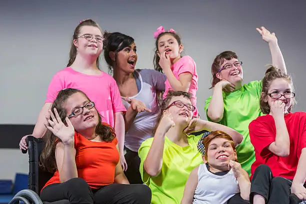 A teacher with a group of seven girls, teenagers and young women with special needs. They have various physical and mental disabilities, including down syndrome, autism and dwarfism.
