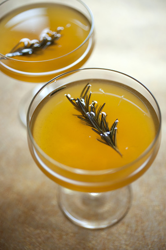 Two craft cocktails garnished with rosemary sprigs