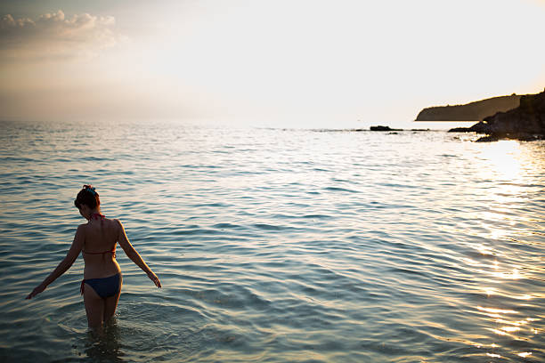 istock Young woman entering water 610254382