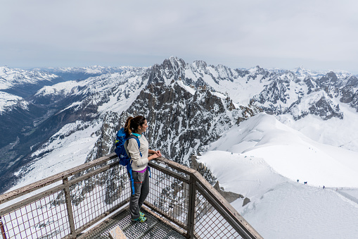 Young woman hiking in the winter and standing at a viewing platform