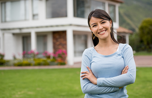 Happy Latin American woman looking very happy outside her house - real estate concepts