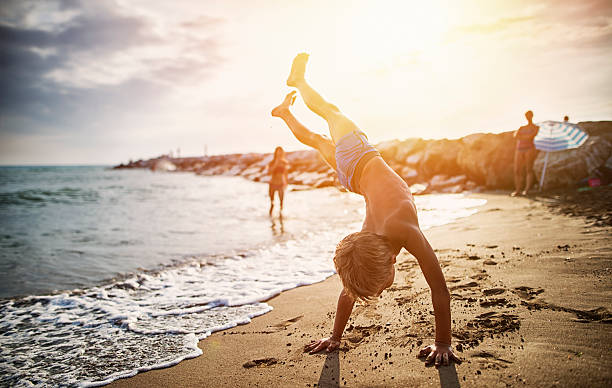 petit garçon pratiquant handstand sur la plage - équilibre sur les mains photos et images de collection