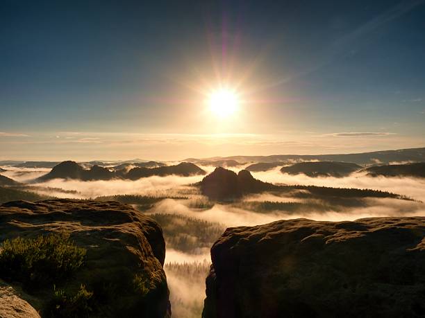istock bright orange daybreak. Sandstone cliff above deep misty valley 610257200