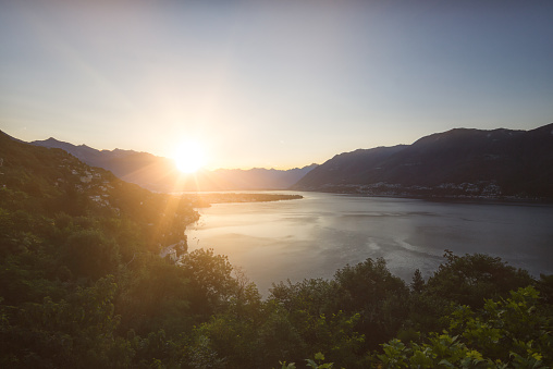 Lake Maggiore is located in the south of switzerland in the canton of Ticino. Early morning photography with sunset just over mountain range in summertime.