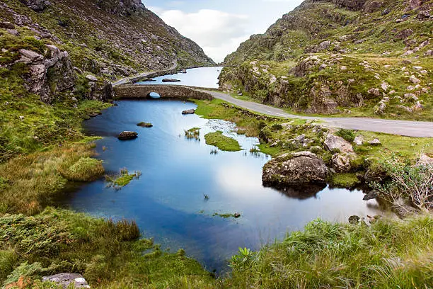 The River Loe and narrow mountain pass road wind through the steep valley of the Gap of Dunloe, nestled in the Macgillycuddy's Reeks mountains of Ireland's County Kerry.