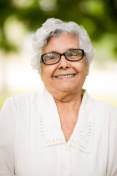 Portrait of a senior latin woman smiling at camera A portrait of a senior latin woman smiling at the camera in a vertical head and shoulder shot. hispanic grandmother stock pictures, royalty-free photos & images