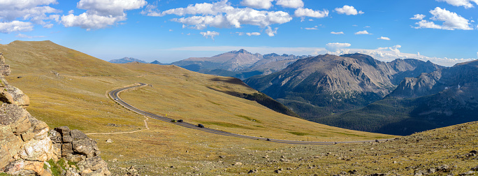 A panoramic evening view of Trail Ridge Road winding through vast alpine tundra at top of Rocky Mountains, with Longs Peak (14,255 feet) rising high in the background, Rocky Mountain National Park, Colorado, USA.