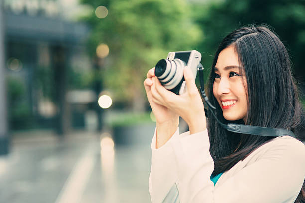 Portrait of a beautiful japanese woman taking a picture with a vinatage camera.