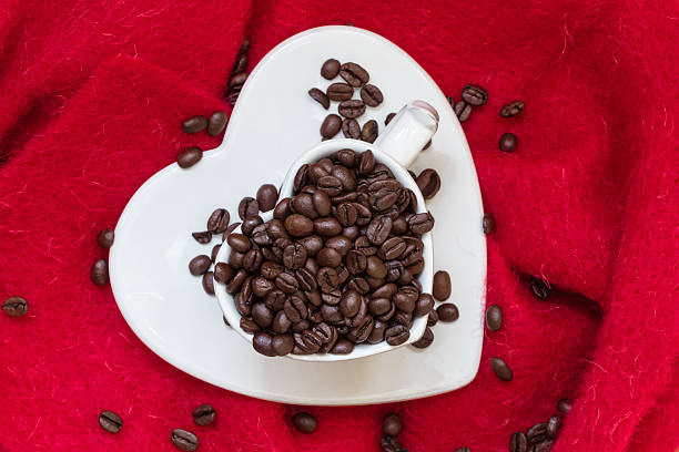 istock Heart shaped cup with coffee beans on red 610263780