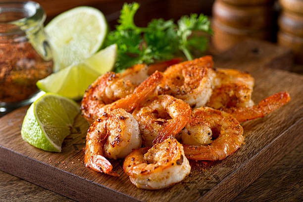 Cajun Shrimp Delicious sauteed shrimp with cajun seasoning and lime on a maple plank. cajun food photos stock pictures, royalty-free photos & images
