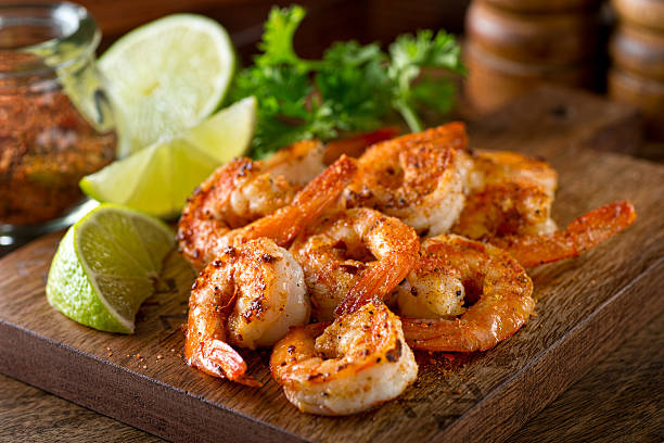 Cajun Shrimp Delicious sauteed shrimp with cajun seasoning and lime on a maple plank. seafood stock pictures, royalty-free photos & images