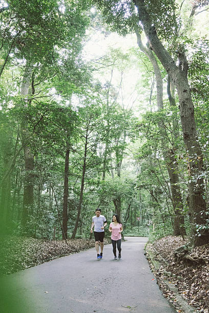 istock Cheerful Japanese couple running outdoors in a park 610407824