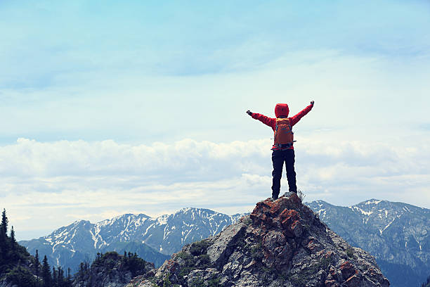 istock cheering successful woman backpacker open arms on mountain peak 610410602