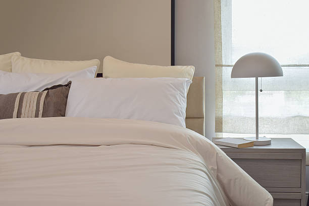 istock Cozy bedroom interior with pillows and reading lamp on table 610412516