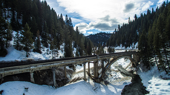 winter storm covers the mountains and a scenic bridge crosses above.